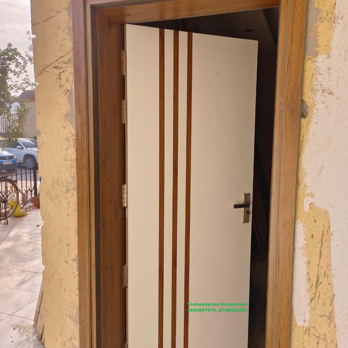 White flush front door with vertical wood-grain inlay strips, set in wood frame