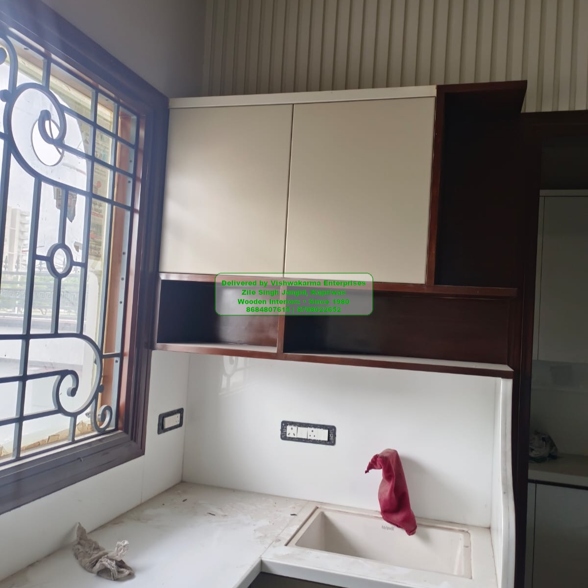 Corner of modular kitchen with cream upper cabinets and fluted wall