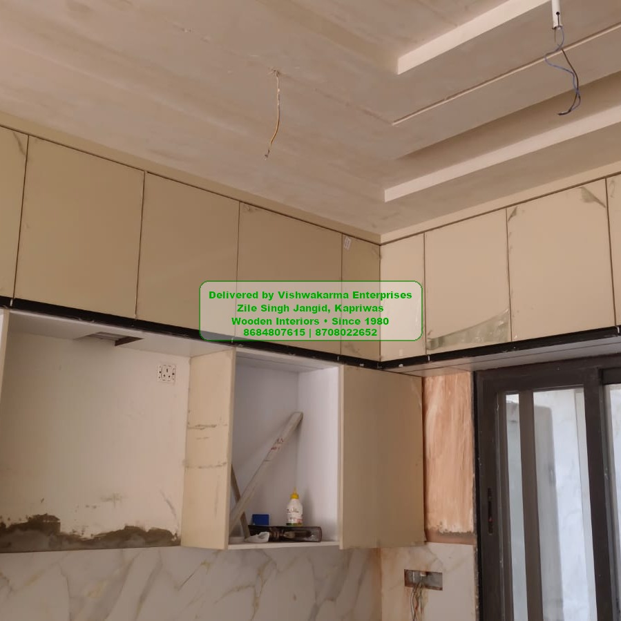 Cream high-gloss modular kitchen with cove-lit false ceiling — Vishwakarma Enterprises install